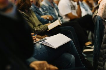 People sitting at a meeting taking notes on their laps